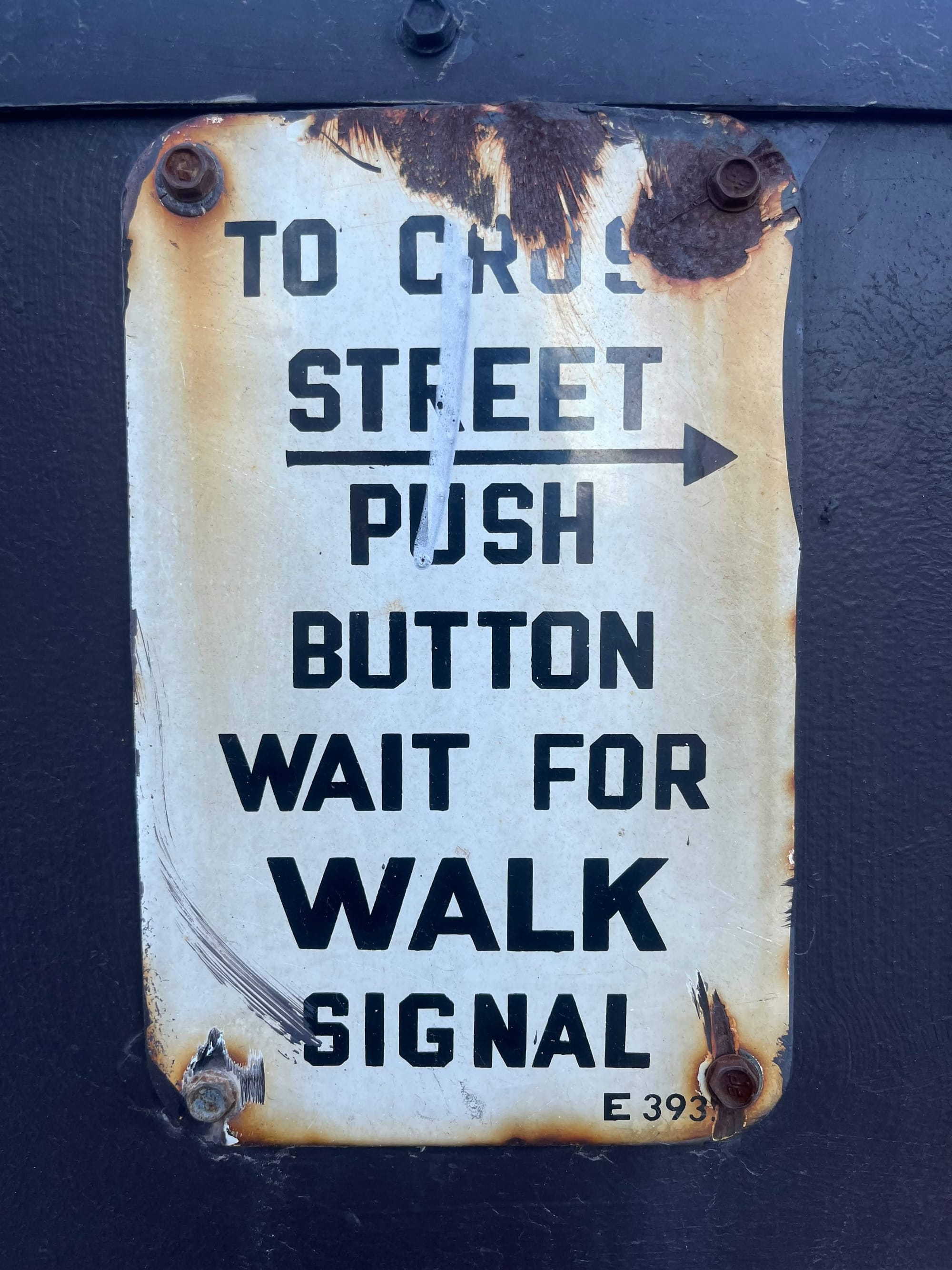 A rusted sign fixed to the side of a building