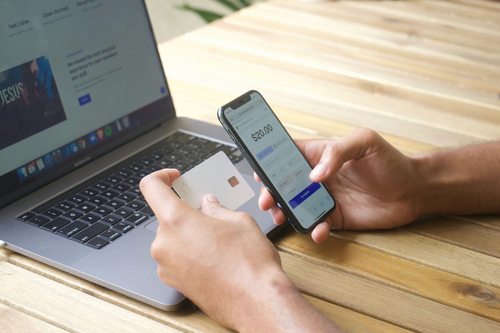 Someone holding a card next to a phone showing a twenty dollar checkout screen