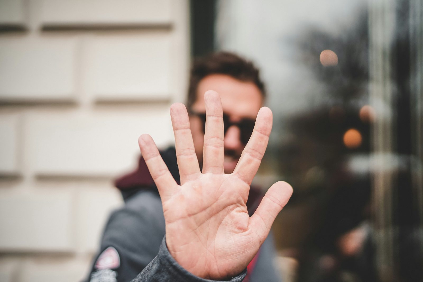 Someone holding up a hand toward the camera, blocking their face