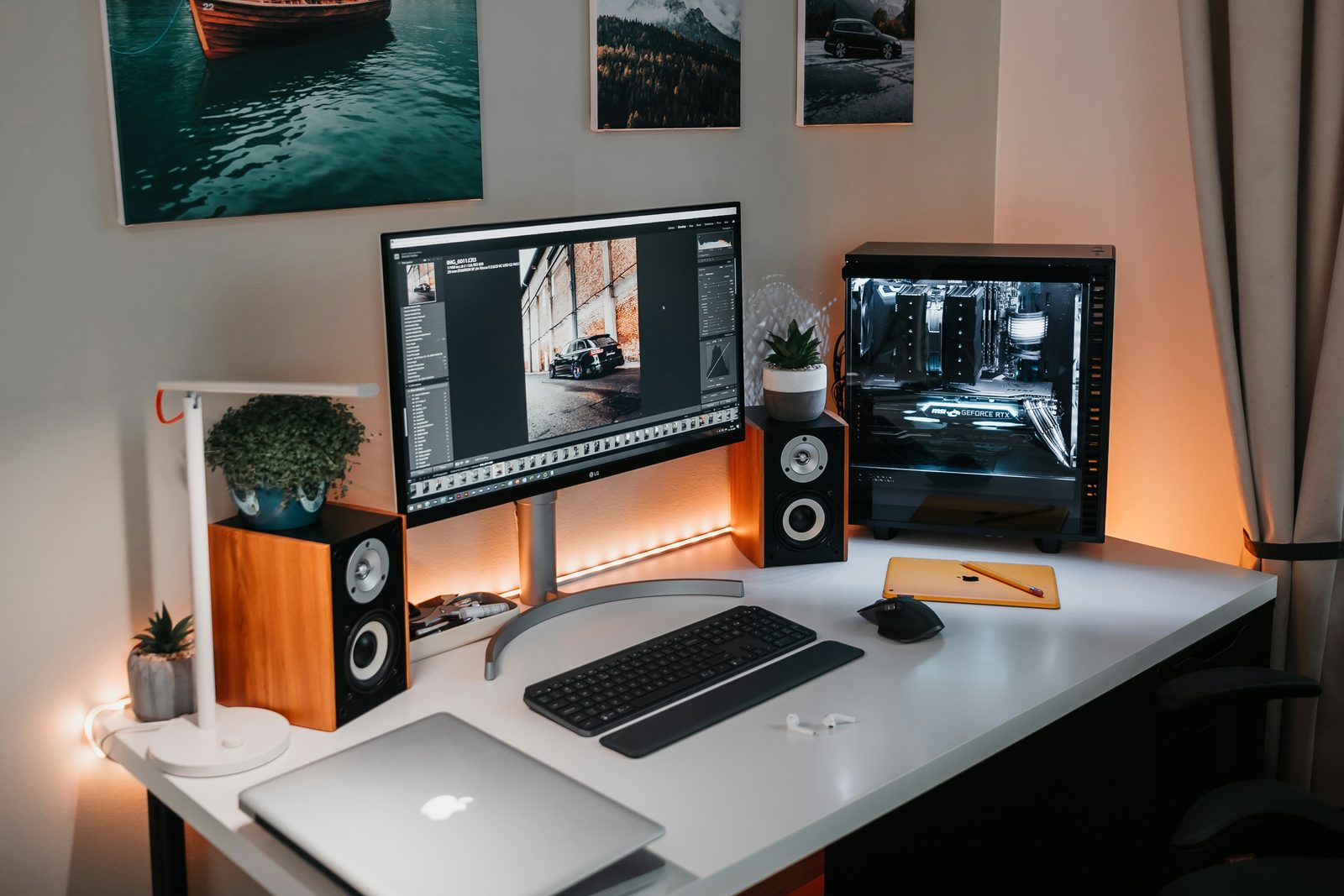 A dual-monitor desk setup with a photo editor open and a PC case glowing on the right