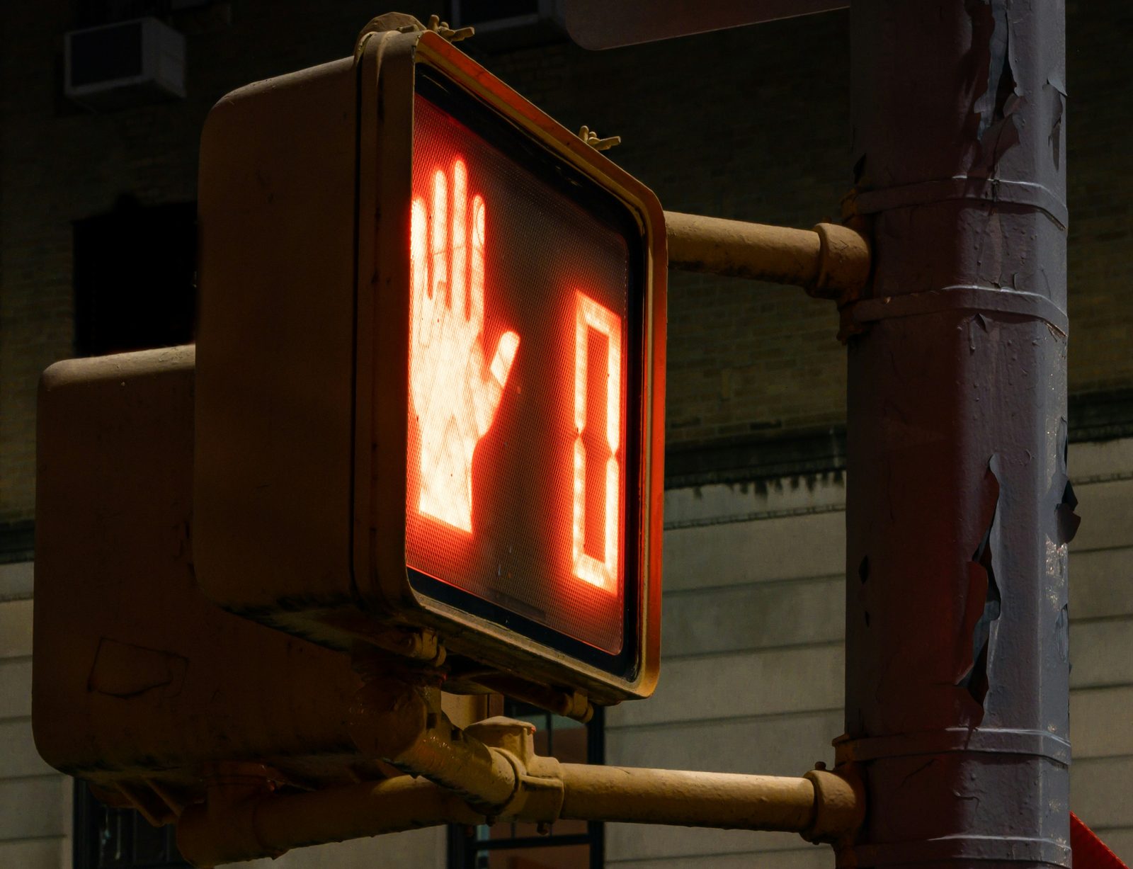 A pedestrian crossing signal at night, lit with a red hand next to a zero