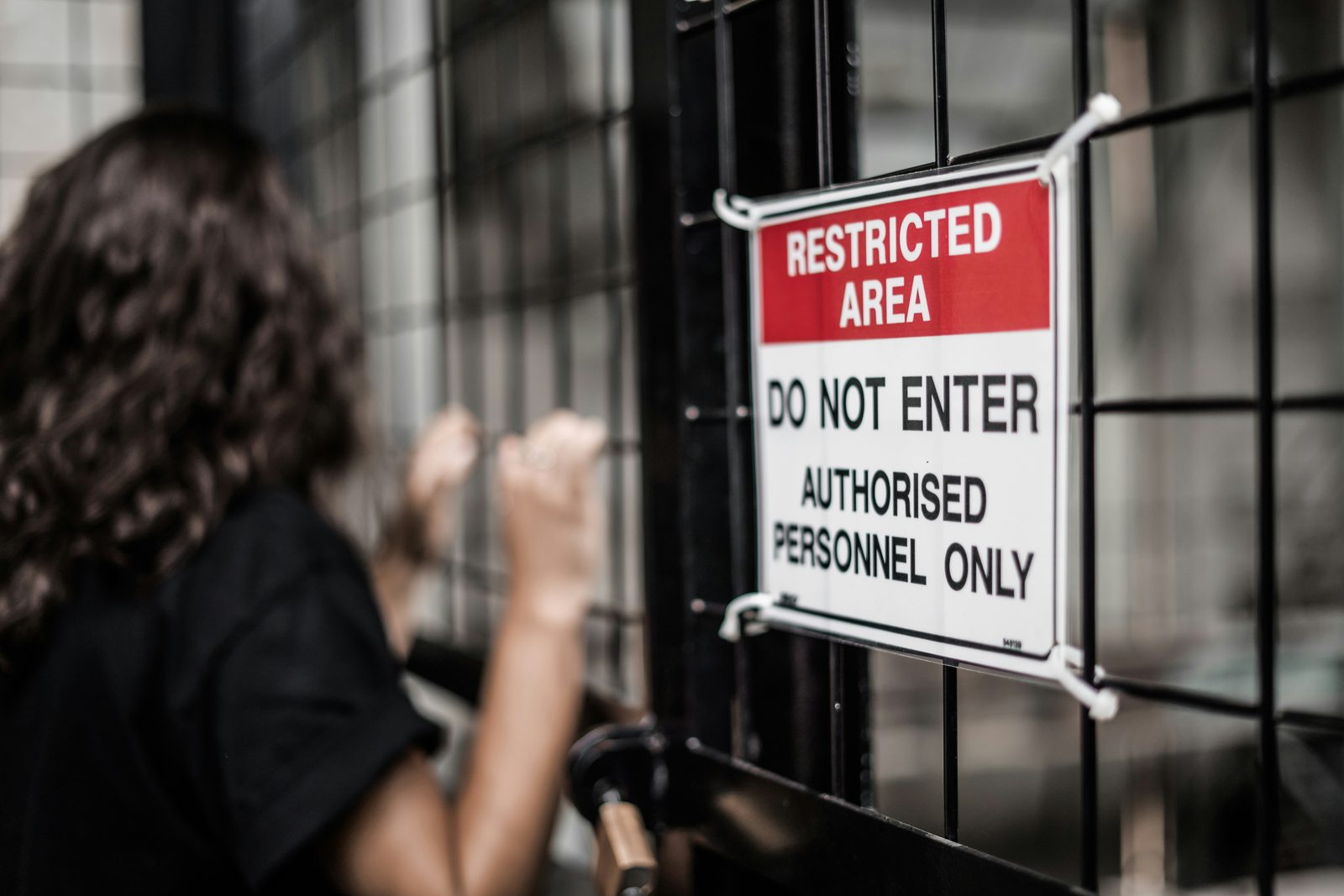 Somebody at a gate next to a sign reading restricted area, do not enter, authorised personnel only