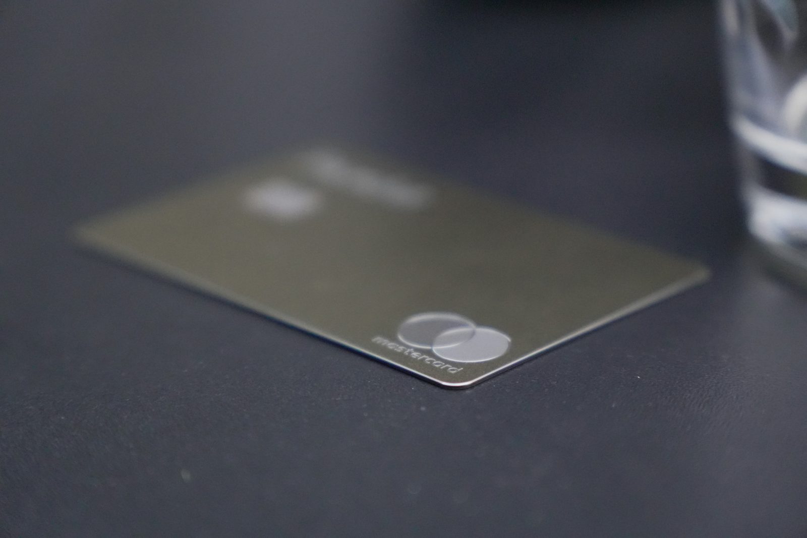 A metal credit card resting on a dark table in low light