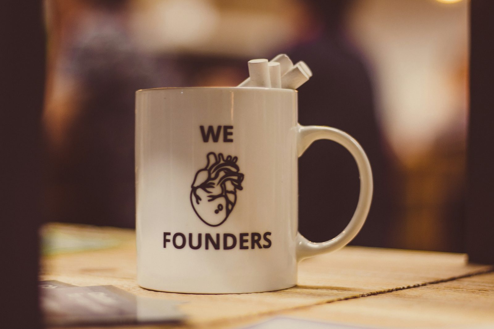 A white ceramic mug with the words we founders and a small heart printed on it, in shallow focus