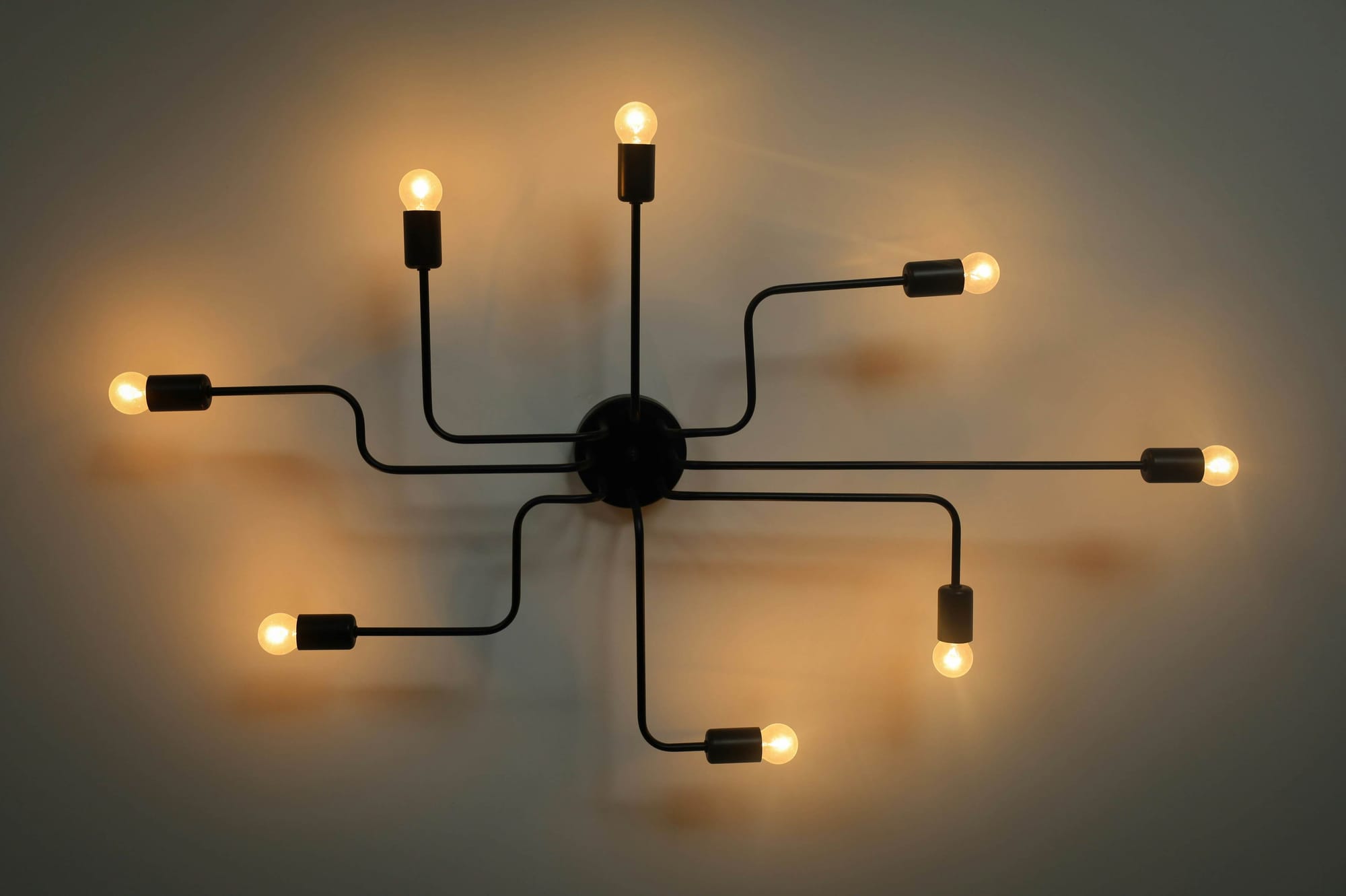 Bare light bulbs on cables radiating from one central hub, like events fanning out from a single source